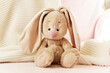 A soft toy rabbit in the nursery on the bed is waiting for the baby. Sweet, delicate toy. The child's favorite toy. Baby sleeping with a hare
