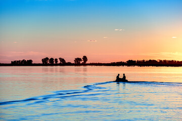 two men navigate the lagoon with a small boat at sunset