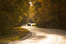 Winding Rual Road Inside Colorful Autumn Forest With Black Car