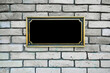 Black commemorative plaque in golden frame fixed on white brick wall