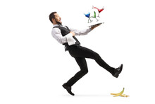 Full Length Shot Of A Waiter Slipping On A Banana Peel And Falling With A Tray Of Coctails