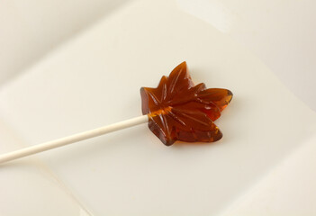 closeup of maple leaf maple syrup lollipop on white dessert plate