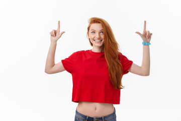 Wall Mural - Photo of happy young woman standing isolated over white wall background. Looking camera showing copyspace pointing