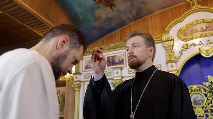 Wall Mural - a priest blesses a bearded man in an Orthodox church after a festive church mass