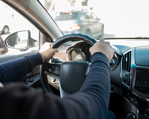 men's hands on the steering wheel of the car