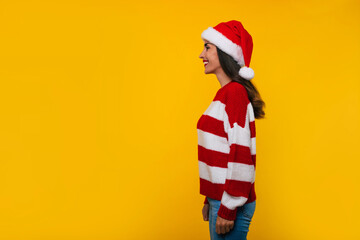 Wall Mural - Side view photo of smiling attractive young woman in Christmas hat isolated on yellow wall