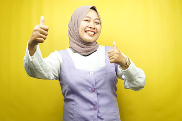 Beautiful young asian muslim woman smiling confident, enthusiastic and cheerful with  hands thumbs up, ok sign, success, good job, success sign, isolated on yellow background