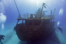 SCUBA Divers Exploring A Shipwreck In Tropical Waters