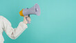 © nisara - Hand holding megaphone and wear PPE suit ,medical glove on green mint  or Tiffany Blue background.