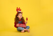 © nellas - Portrait of happy little  girl Christmas  holding present box and looking at camera on yellow background