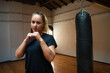 Attractive young woman in combative position. Woman in black sport clothes showing fists at camera. Sport, healthy lifestyle, boxing concept