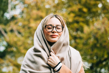 Wall Mural - Portrait of beautiful young woman in eyeglasses, enjoying autumn weather in the park. Woman walking in the autumn park.