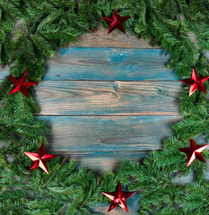 Canvas Print - Top view of a complete wreath and red stars in circle border on blue aged wooden planks for the winter holiday season of Christmas or New Year background