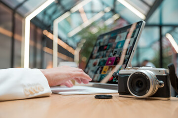 A freelance photographer works remotely, a thin mobile computer with a photo on the screen and a camera in the foreground. Creative work, retouching or creating designs.