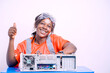 image of cheerful young african lady, with protective eye glass and thumb up sign, sitting in front of system unit- hardware technician concept