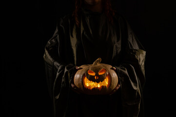 The witch is holding a pumpkin jack about a lantern glowing in the dark. Halloween.