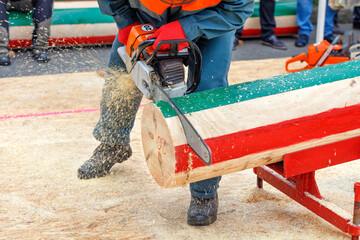 Man holds a chainsaw in his hands and cuts a marked log for accuracy on competition of lumberjacks.