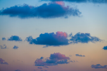 Wall Mural - Natural background, stunning view of some fluffy clouds on a purple and orange sky during a beautiful sunrise. Sardinia, Italy.