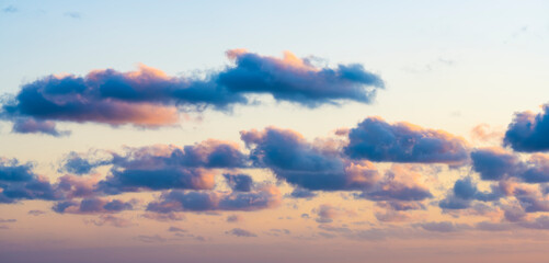 Wall Mural - Natural background, stunning view of some fluffy clouds on a purple and orange sky during a beautiful sunrise. Sardinia, Italy.