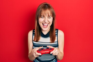 Poster - Redhead young woman playing video game holding controller smiling and laughing hard out loud because funny crazy joke.