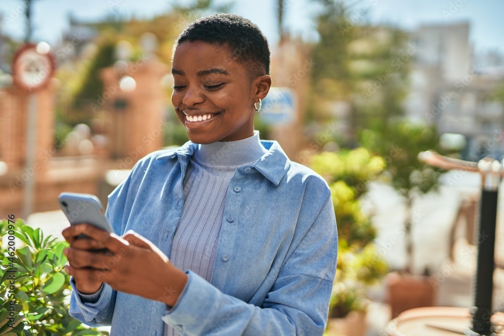 Young african american woman smiling happy using smartphone at the city ...