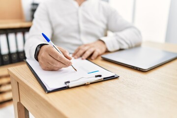 Businessman writing on clipboard at the office.