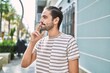 © Krakenimages.com - Young hispanic man smiling confident smoking cigarette at street