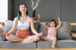 © Вадим Каштанов - Young mom practices yoga on couch with her little daughter. Lotus position.