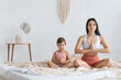 © Вадим Каштанов - Happy family mother and toddler doing home yoga. Meditate in lotus position.