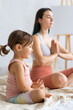 © Вадим Каштанов - Young mom practices yoga on couch with her little daughter. Meditation in lotus position.