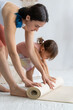 © Вадим Каштанов - Young mother with her little daughter is rolling out yoga mat. Yoga Home.