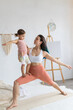 © Вадим Каштанов - Young mother with little daughter practice yoga home. Warrior pose.