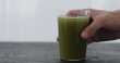man hand take green matcha drink in tumbler glass from black oak table with copy space