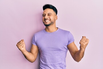 Young arab man wearing casual clothes very happy and excited doing winner gesture with arms raised, smiling and screaming for success. celebration concept.