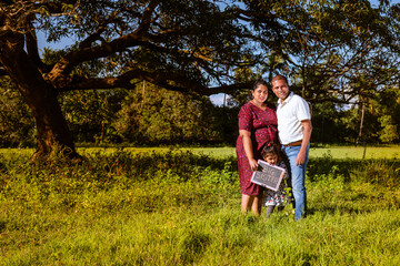 Wall Mural - Pregnant mother, father and toddler daughter spending time outdoors. Happy maternity scene of mother father and toddler expecting a second child. Maternity photoshoot of a happy family 