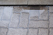 A puddle after rain on an uneven tile surface. Improperly laid gray paving slabs. Errors in paving stone laying. Wear and the influence of atmospheric conditions on paving slabs.
