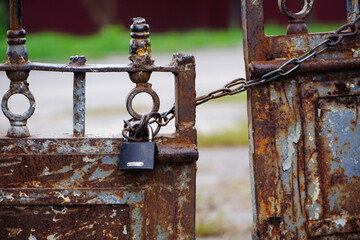 Wall Mural - Rusty old padlock on metal gate closeup. Dirty lock on closed. lock on chains. Protection, security and safety concept. Private property entrance. old rusty iron texture.