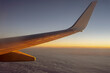 Lot samolotu przy wschodzie słońca, widok na skrzydło samolotu. 