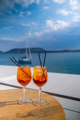 Wall Mural - Orange drink or cocktail standing at the little table at the restaurant or cafe with sea background