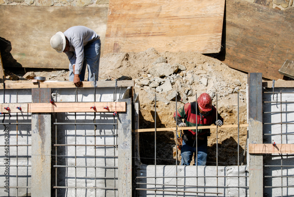 Construction workers installing wooden ground boards on a retaining ...