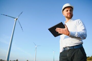 Electrical engineers working at wind turbine power generator station with laptop computer