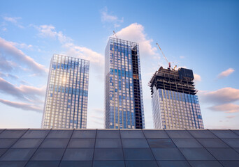 Poster - Skyscraper glass facades on a bright sunny day with sunbeams in the blue sky. Economy, finances, business development activity concept. Bottom up view