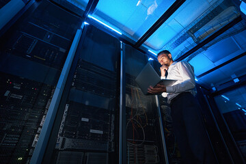 Wall Mural - IT technician analyzing data from laptop in server room