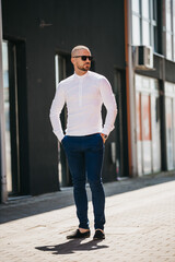 Canvas Print - Cool handsome Caucasian man wearing an elegant white shirt and sunglasses posing outdoor