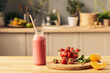 © pressmaster - Bottle of homemade smoothie, fresh strawberries, mint leaves and two orange pieces on kitchen table