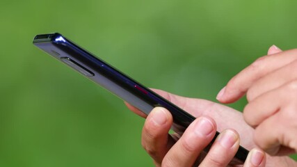 Phone. Hand of girl using smartphone outside, swiping and scrolling on screen. Close-up of young women hand.