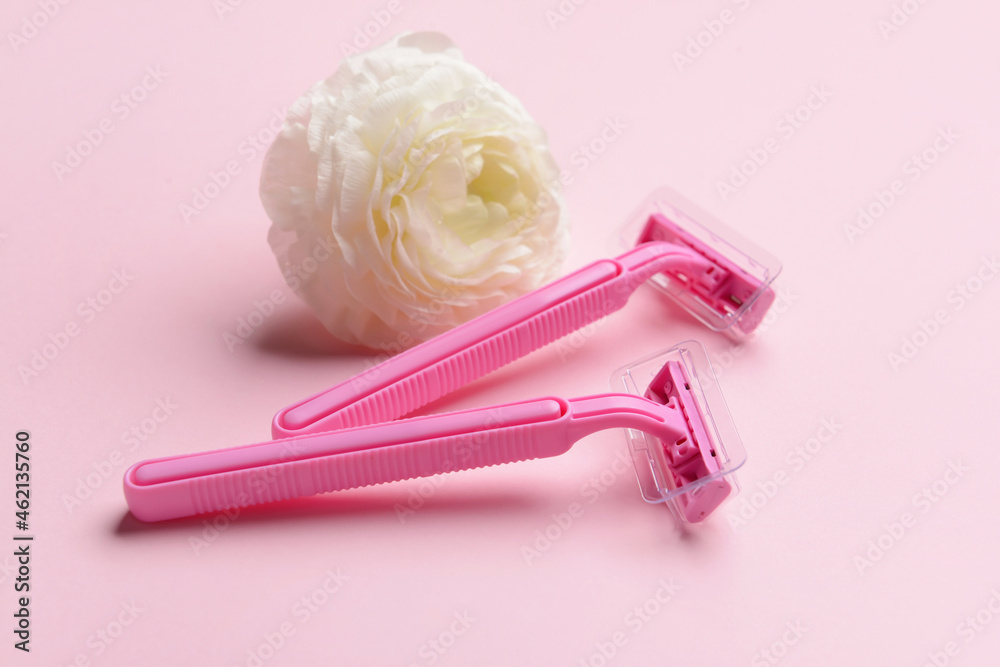 Safety razors and flower on pink background