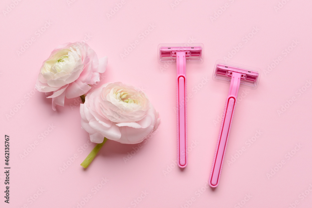 Safety razors and flowers on pink background
