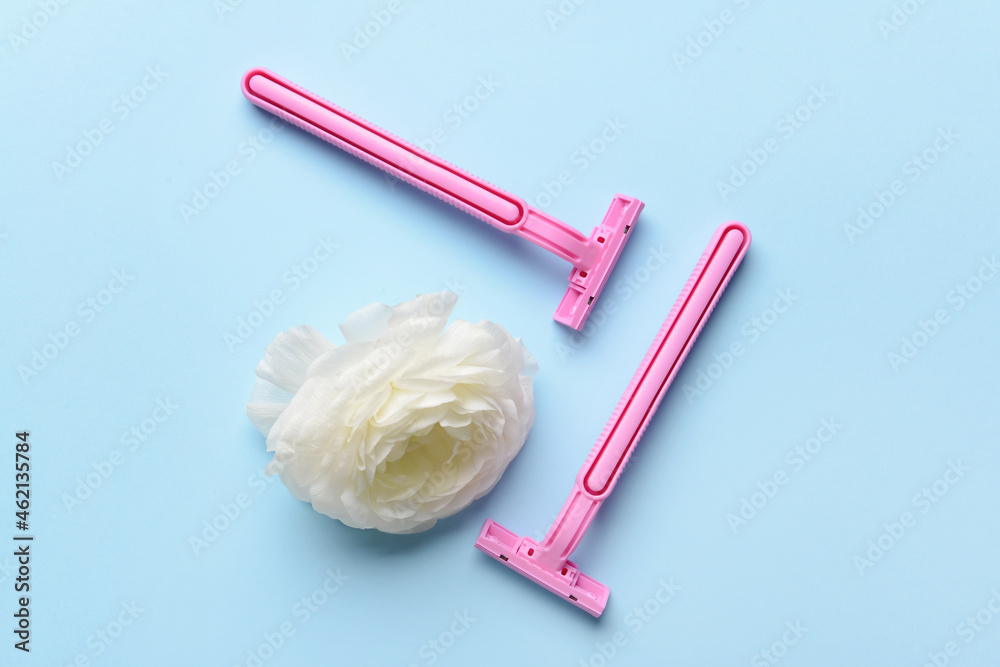 Safety razors and flower on blue background