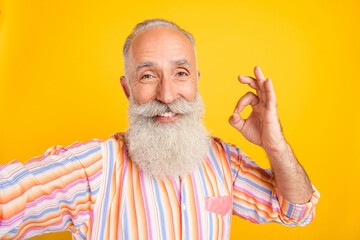 Sticker - Photo of pretty charming age gentleman wear striped shirt smiling recording video showing okey sign isolated yellow color background